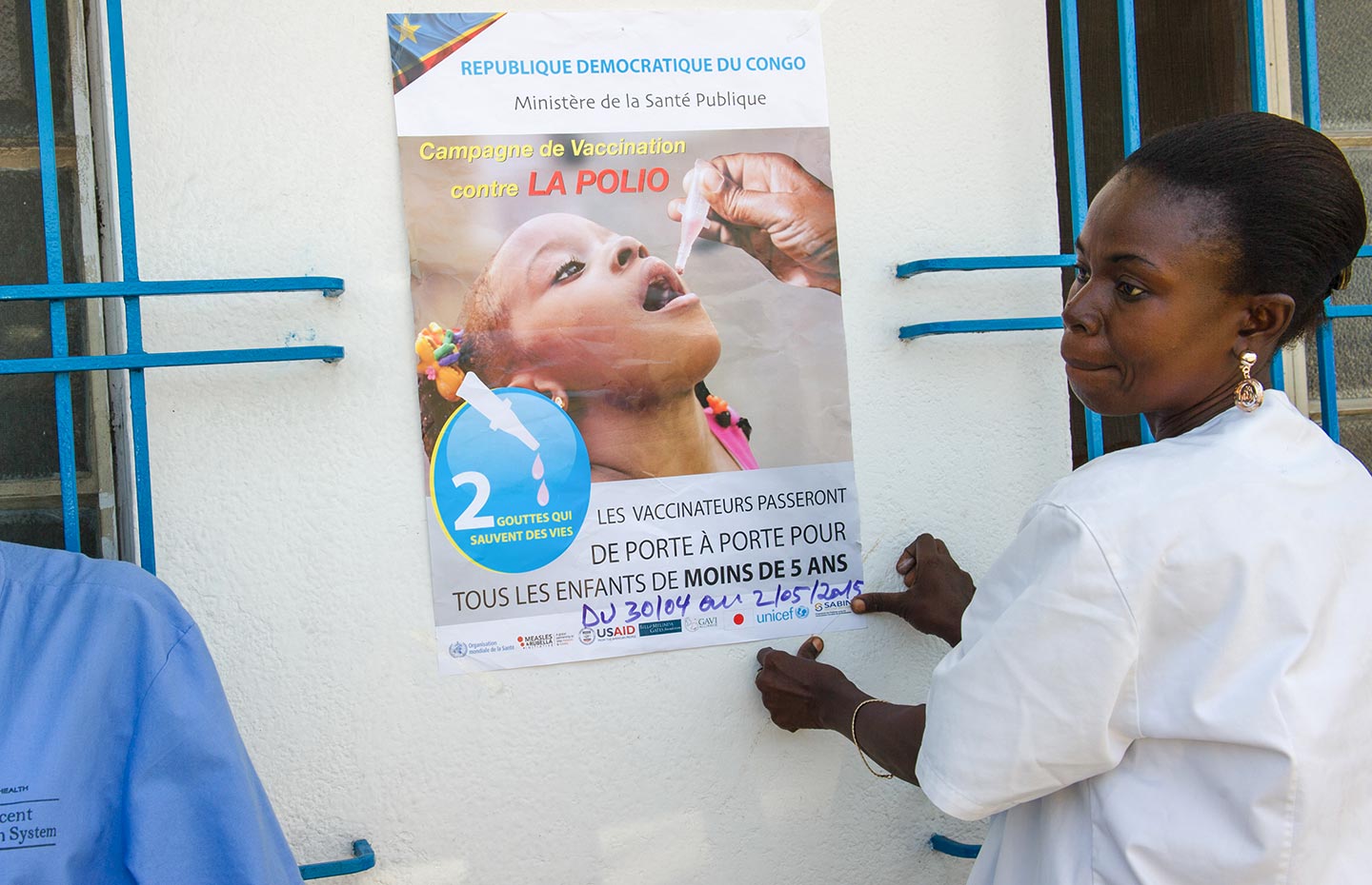 GAVI/2015/Phil Moore- A nurse attaches a poster advertising a door-to-door polio vaccination campaign in Kinshasa, Democratic Republic of the Congo, on April 27, 2015