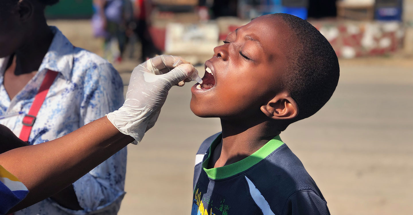 Woman receiving the oral cholera vaccine to a young boy. Credit: Gavi/D G Rowe.