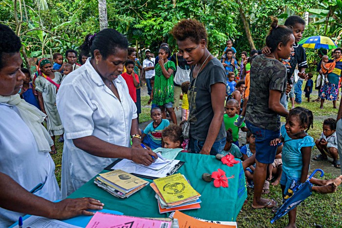 Officer-in-charge Daisy Basa (centre) checks a child’s vaccination card at the Malahang Health Clinic. More than 2900 health workers, vaccinators and volunteers have been mobilised to vaccinate almost 300,000 children under five years old in Morobe, Madang and Eastern Highlands provinces.