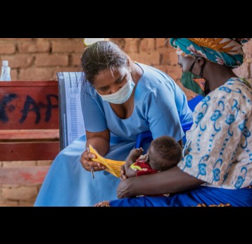 A health worker checks on a child’s health passport – Credit UNICEF Malawi