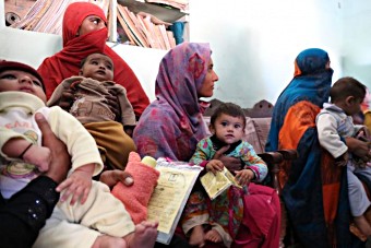 Mothers waiting to get their children immunised at a vaccination site in an area of Lahore