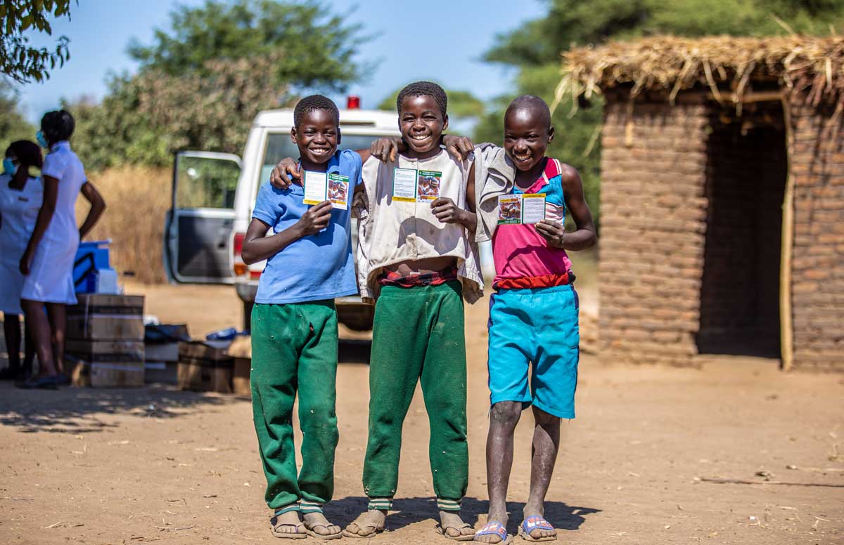 Three boys standing together with their TCV vaccination cards. Credit: UNICEF
