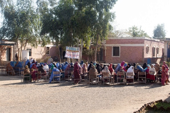 over forty women sat on foldable chairs with their backs to photographer