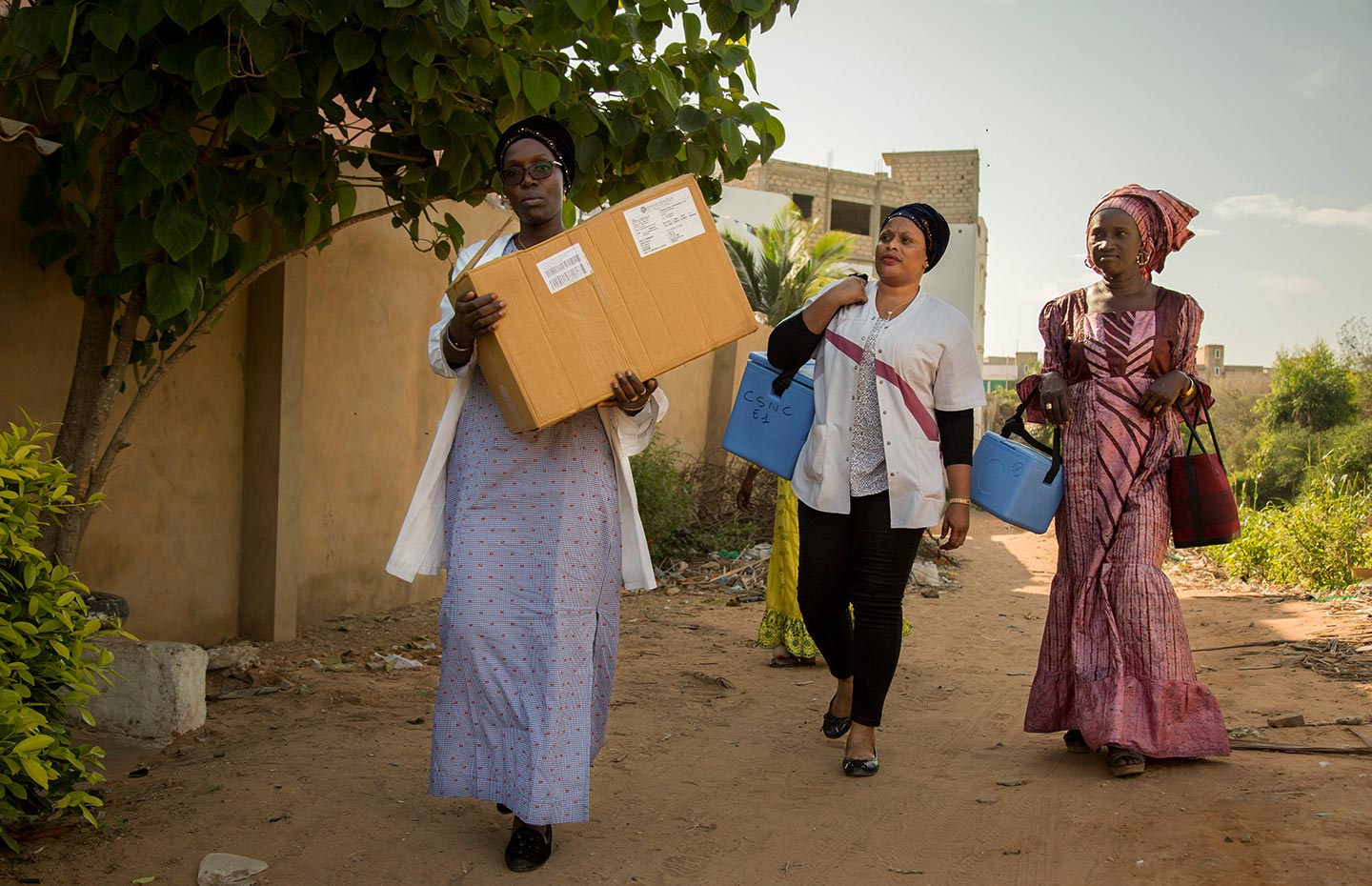 Gavi/2018/Simon Davis- Health workers from the Dakar North District immunisation "outreach" team set out on foot after reaching the end of the built road. They are taking vaccines to families in Nabisouikr, one of Dakar's slum areas