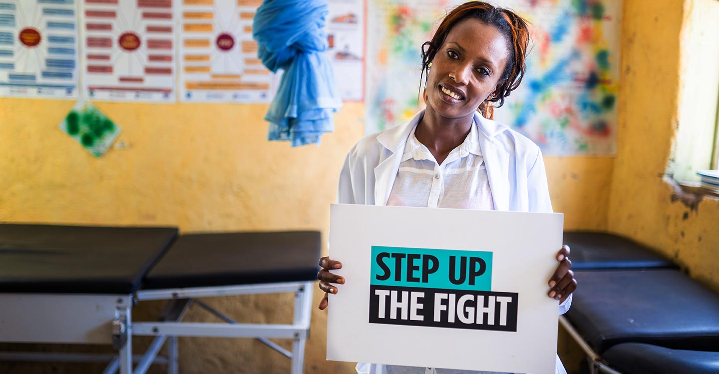 health worker holding up outreach poster against MMR