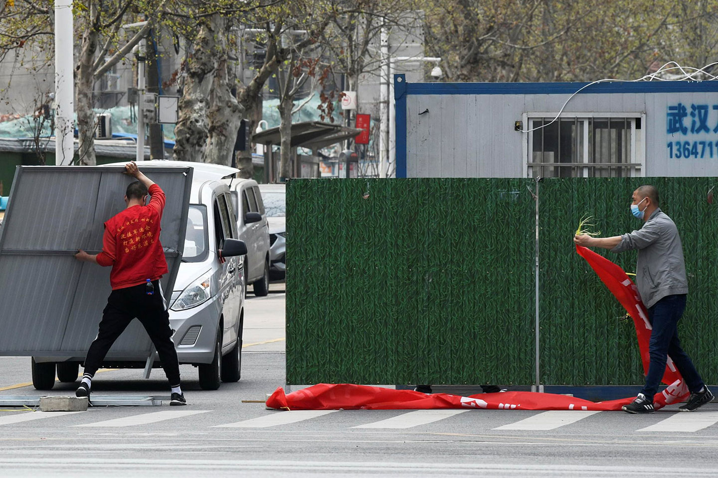 Image from The Guardian article: Workers wearing face masks remove barriers on a street in Wuhan as the Chinese city has started to loosen its coronavirus lockdown Photograph: China Daily/Reuters Image from The Guardian article: Workers wearing face masks remove barriers on a street in Wuhan as the Chinese city has started to loosen its coronavirus lockdown Photograph: China Daily/Reuters