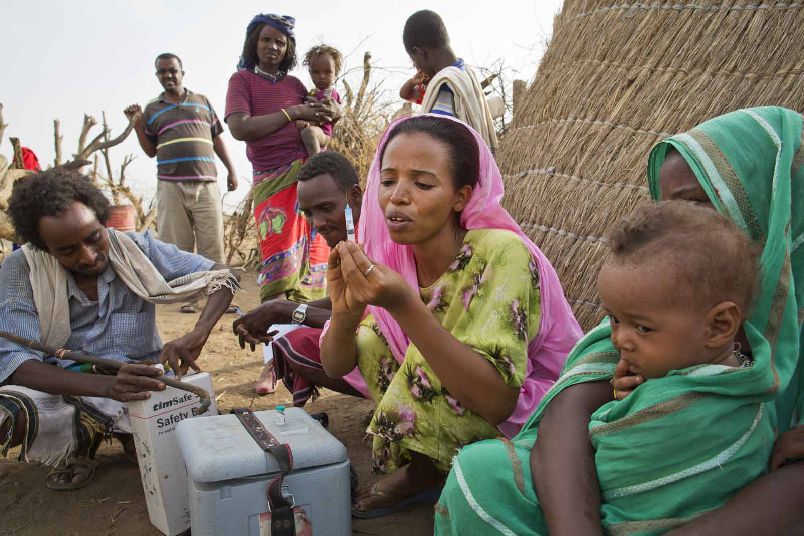 Sister Sofia prepares a vaccine for Hamed Dawd as other villagers wait their turn. Outreach workers have to estimate the ages of children, because parents are generally unsure of precise birth dates.