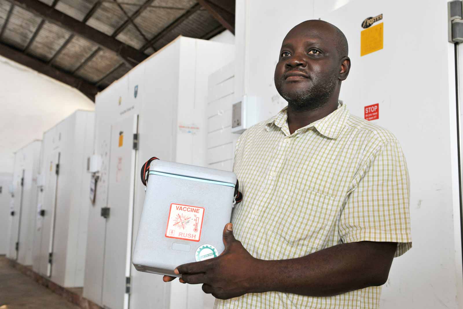 Onojo Otowo, 43 ans, Responsable de la distribution des vaccins au Centre national d’entreposage frigorifique à Abuja, montre la glacière utilisée par le personnel itinérant en charge de la vaccination. Ce centre dispose d’une capacité d’entreposage réfrigéré de 73 000 litres et distribue des vaccins dans tous les Ministères nigérians de la santé. Dans ce centre de stockage où sont entreposés des vaccins
