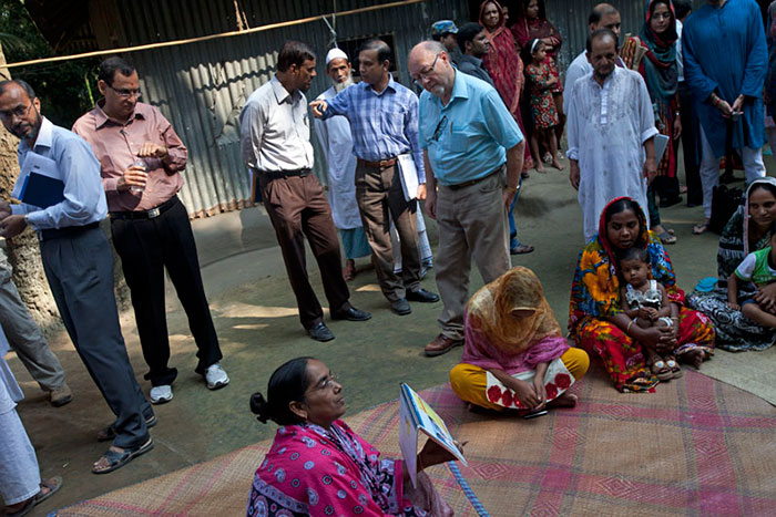 Jim Dobbin (centre, in blue shirt), a UK Member of Parliament on a fact-finding mission to learn more about Bangladesh’s immunisation success story, watches as a BRAC health worker teaches mothers how to recognise symptoms of pneumonia.
