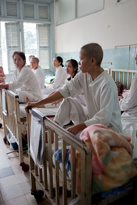 Patients sit on their beds in the women’s cervical cancer ward of the Ho Chi Minh City hospital in Vietnam. Linked to the cancer burden, patients must frequently share beds.