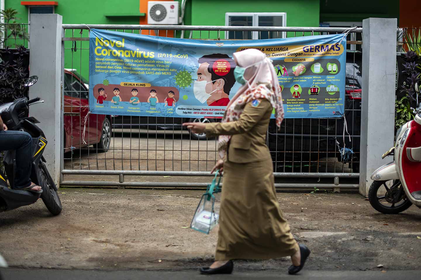 Puskesmas staff were passing in front of an information poster about Covid-19 in front of the Puskesmas in East Jakarta, Indonesia on 30 March, 2020.  Credit: UNICEF/2020/Arimacs Wilander