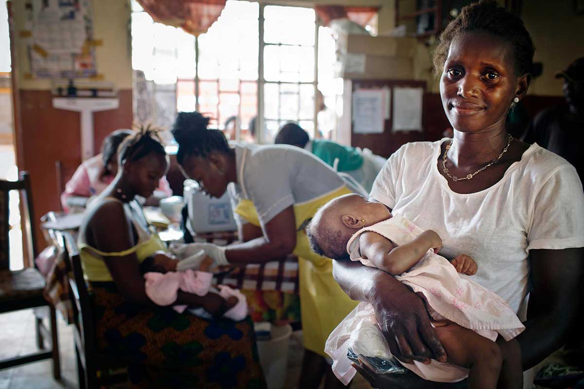 A woman waits with her daughter to be vaccinated at a maternal and child health clinic in a health centre in Freetown, Sierra, Leone on 17 February 2016. Gavi/2016/Kate Holt/Sierra Leone