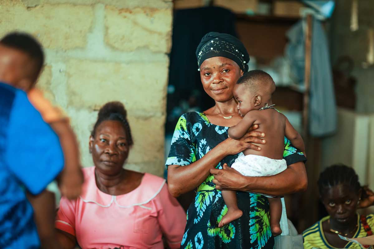 A mother stands with her newborn during the nationwide malaria vaccine campaign at a health centre in Sierra Leone. Credit: Gavi/2024/Dominique Fofanah