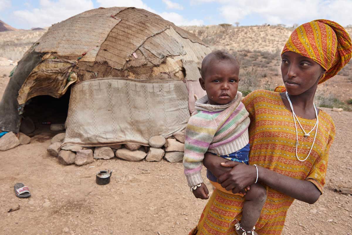 A woman stand with her child outside her traditional hut with her child in the village of Abdoya, Djibouti. Credit: UNICEF/Shehzad Noorani