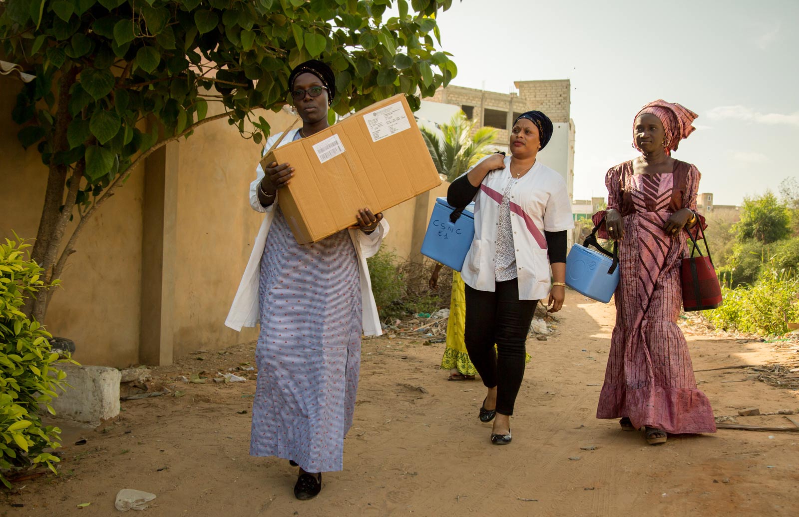 Gavi/2018/Simon Davis- Health workers from the Dakar North District immunisation "outreach" team set out on foot after reaching the end of the built road. They are taking vaccines to families in Nabisouikr, one of Dakar's slum areas