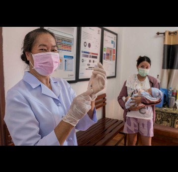 A mother and child attend a routine vaccination session in Lao PDR while a health worker prepares a vaccine. Credit: Gavi/2024/Running Reel