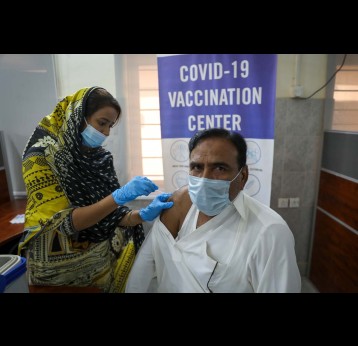 A health worker in Pakistan administering a COVID-19 vaccine to a man during a vaccination clinic. Credit: Gavi/2021/Asad Zaidi