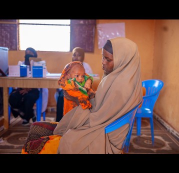 Muslima Ahmed holds her child as she waits for him to receive a dose of vaccine at the outreach vaccination facility in Somalia. Gavi/2024/Mohamed Abdihakim Ali