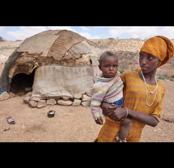 A woman stand with her child outside her traditional hut with her child in the village of Abdoya, Djibouti. Credit: UNICEF/Shehzad Noorani
