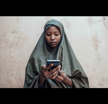 Nigerian woman using her phone. Credit: KC Nwakalor for USAID