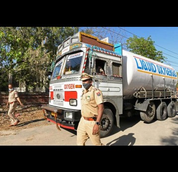 Police personnel escort a truck carrying medical liquid oxygen to the Guru Nanak Dev hospital in Amritsar, India, on April 24, 2021. Photo by NARINDER NANU/AFP via Getty Images