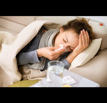 Sick woman sneezing into tissue.