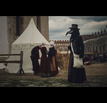 A masquerade historical scene reconstruction. Plague doctor in medieval old town.