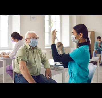 Male senior citizen waiting to receive his vaccine. Asian doctor in face mask administering shot to mature man.