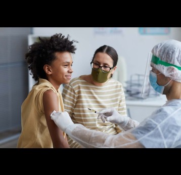 Side view portrait of teenage boy smiling happily during COVID vaccination in clinic