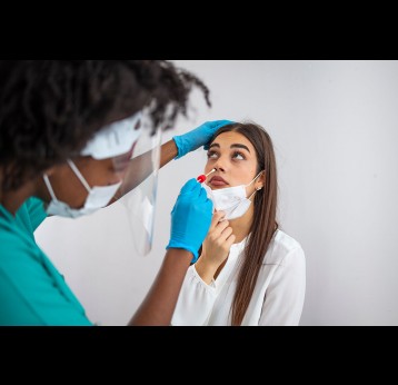 Doctor in protective workwear taking nose swab test from young woman. Close-up of woman having PCR testing at the hospital.