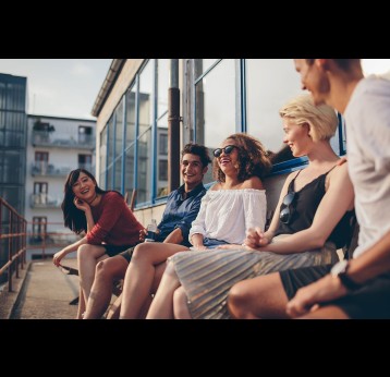 Multiracial group of friends sitting in balcony and smiling.