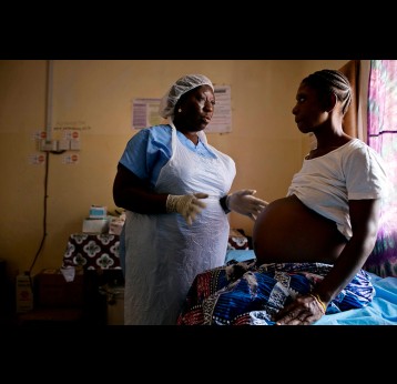 A midwife examines a pregnant woman at a health clinic. Gavi/2016/Kate Holt