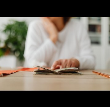 Woman sitting behind a desk and counting money and receipts. Photo by Karolina Grabowska from Pexels