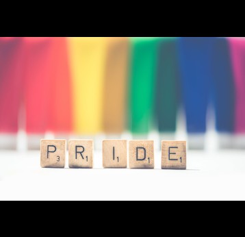 Selective focus photograph of Scrabble tiles spelling PRIDE against a rainbow backdrop. Photo by Ylanite Koppens from Pexels
