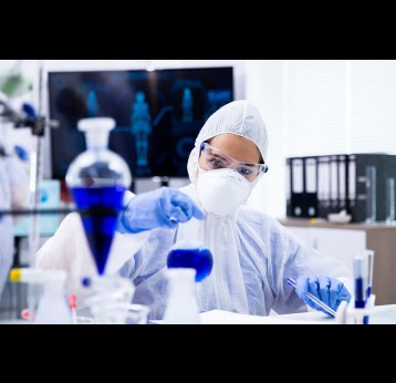 Researcher in full protective equipment in a lab.