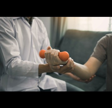 A physiotherapist helping patient with lifting dumbbells exercises.