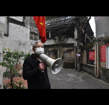 Mr Han Cong Khanh holds a loudspeaker in an alley of his neighbourhood in Hanoi, Vietnam.