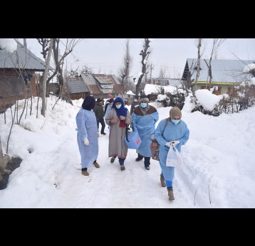 Health workers walk through snow-clad roads in the village of Khag to vaccinate people who could not reach health centers.