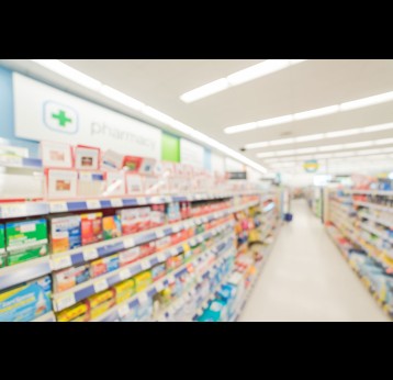 Blurred abstract background inside pharmacy store with arranged variation of pharmaceutical and medical supplies product in label on shelves display.