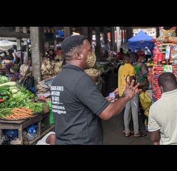 Koffi Guelih de la Brigade Jeunes Anti-COVID-19 parle de la pandémie aux commerçants du marché. Crédit : Nephthali Ledy