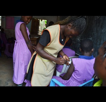 Mercy Nyakecho, a nurse at NAWEC, vaccinating girls at Bright Valley Walukuba Primary School