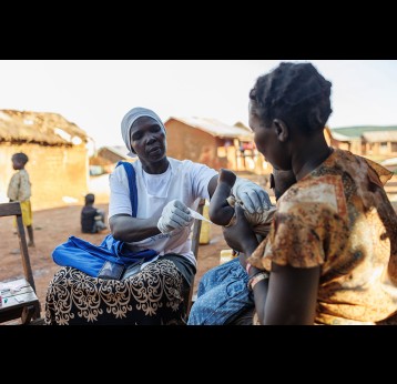 Mutesi Fatuma measuring the temperature of Wanga Glady's child. Fatuma has been trained to carry out malaria assessments and dispense medicine for children under five years. Living Goods/2022/Jjumba Martin