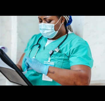 A nurse with face mask and gloves looks at a chart. Credit: Laura James on Pexels