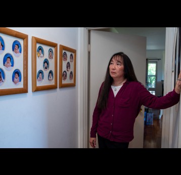 Angela Tang, whose son came down with a baffling illness several years ago, looks at baby pictures of her three children at their home in the Los Angeles suburbs. Visual: Monica Almeida
