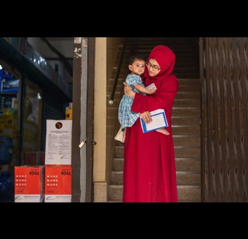  A mother holds her child clutching a vaccination card outside in Bangladesh. Credit: Simprints/2023/Ashraful Arefin