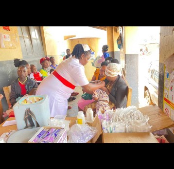 Namusoke giving a polio vaccine to a baby under a shade at Kyegegwa Hospital. Credit: John Agaba