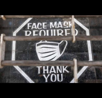 On the window of a closed business in New York City, pictured in March 2025, an old sign asks customers to wear a mask to prevent the spread of Covid-19. Visual: Spencer Platt/Getty Images