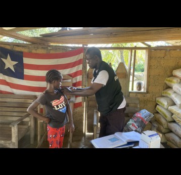 Jerry Karn, a rural vaccinator, administers the HPV vaccine to a nine-year-old during an outreach in Zuoplay, Nimba County. Credit: Tina S. Mehnpaine