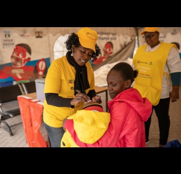 Janet Maloba, 27, holds her son as he receives the Oral Cholera Vaccine at vaccination facility. August 10th, 2023. Kajiado East, Kenya. Credit: Gavi, Kelvin Juma
