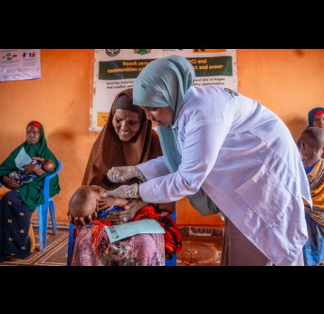 A health worker in Somalia administers an oral dose of vaccine to a child, held by his grandmother. Credit: Gavi/2024/Mohamed Abdihakim Ali